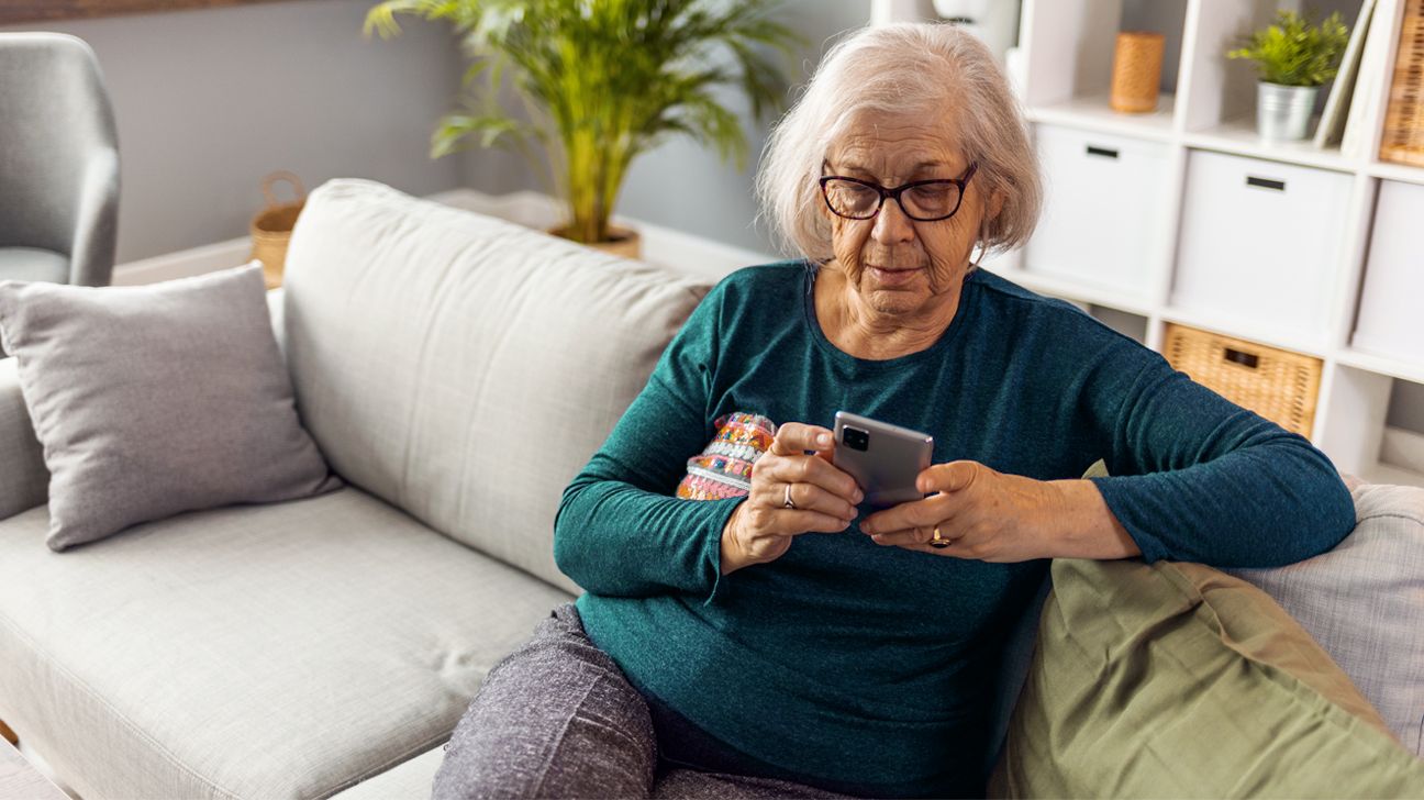 Senior woman on a couch looking a smartphone. 