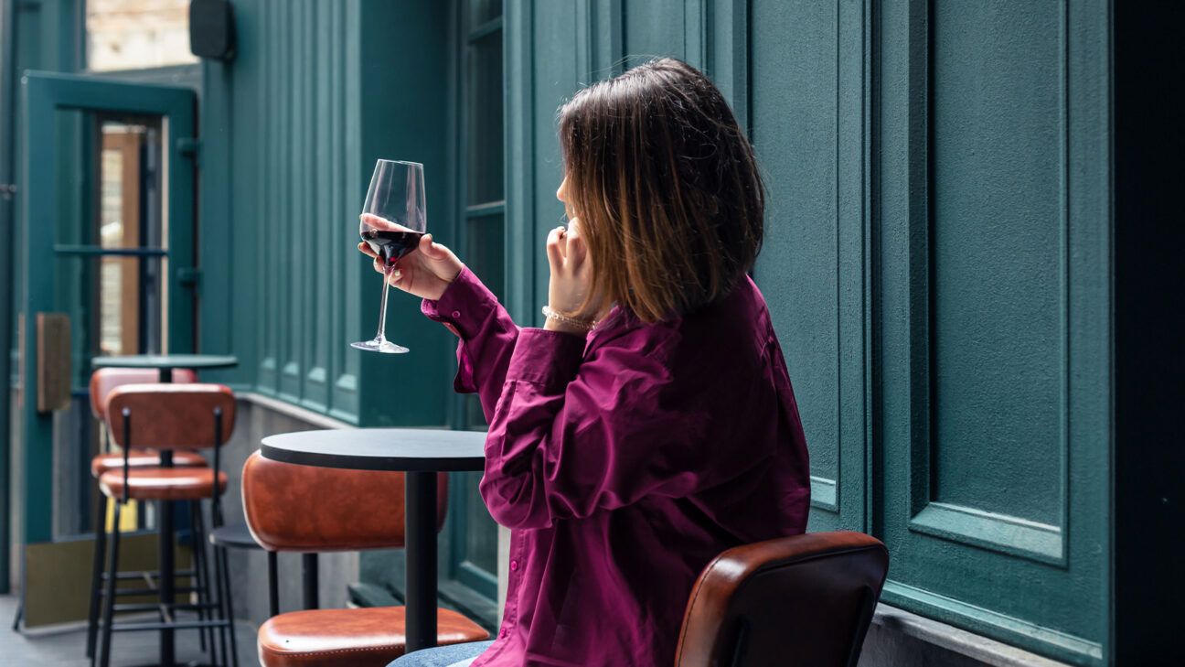 Female drinks a glass of red wine indoors