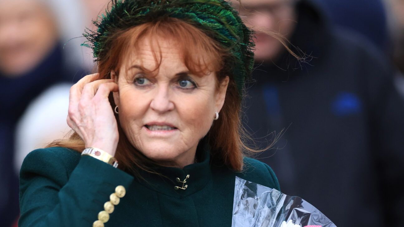 Sarah Ferguson walks outside in a green hat and jacket