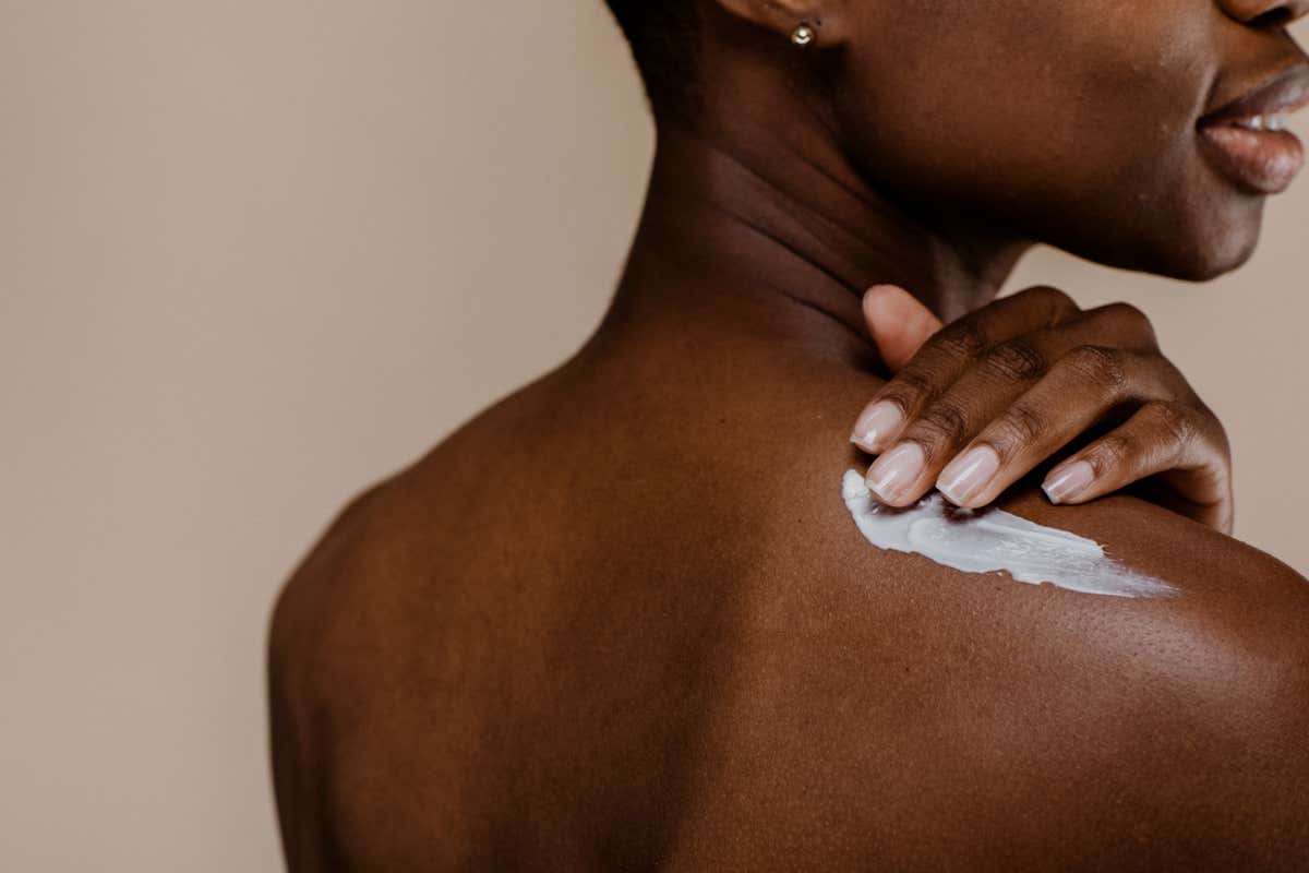 Woman applying body cream to her skin