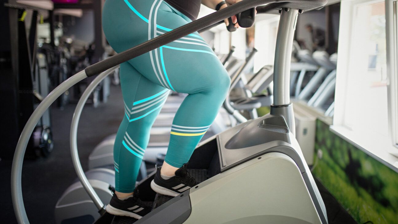A person in blue leggings uses a stairmaster machine.